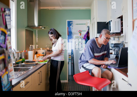 Ein paar verbringen das Wochenende in der Küche, wo die Frau kocht, während Ehemann das Rezept im Internet sieht Stockfoto