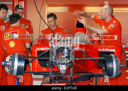 (Dpa) - Mechanik des Ferrari-Teams arbeiten an den Rennwagen des deutschen Formel 1-Weltmeister Michael Schumacher in der Boxengasse auf die Rennstrecke in Melbourne, Australien, 5. März 2003. Die Formel wird-1-Saison 2003 dieses Wochenende in Melbourne geöffnet. Stockfoto