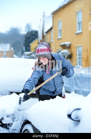 Eine Autofahrer löscht Schnee aus ihrem Auto in das Dorf von Badminton Gloucestershire UK Stockfoto