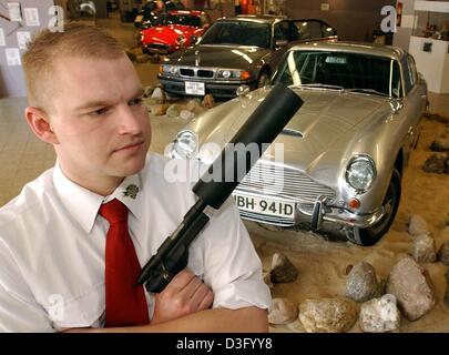 (Dpa) - stellt Wachmann Jan Erke mit einem Rauschen reduziert Gewehr in einem James-Bond-ähnlichen Pose vor dem ursprünglichen Bond-Auto, eine silberne Aston Martin DB5, in das erste Spy Museum (Spionagemuseum) Schneverdingen, Norddeutschland, 24. April 2003. Im Museum etwa 10.000 Objekte ausgestellt sind, angefangen bei BHs mit eingebautem Miniatur-Kamera Geheimagent Koffer und komplette w Stockfoto