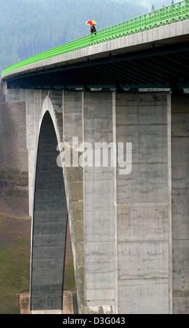 (Dpa) - auf dem 60m hohen Schwarzbachtal-Brücke, zwei Männer halten einen bunten Regenschirm, in der Nähe von Gehlberg, Deutschland, 20. April 2003. Die Brücke ist 325m breit und führt über ein Tal zwischen Ilmenau und Suhl. Es ist Teil der sogenannten Waldautobahn (Wald-Autobahn), eine Autobahn von 222km durch den Wald führt. Seine Konstruktion ist einer der 17 Verkehrsprojekte Deutsche u Stockfoto