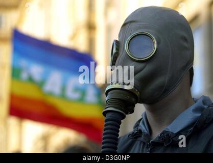 (Dpa) - ein Anti-Kriegs-Demonstranten trägt eine Gasmaske, als Zeichen des Protests gegen den Krieg mit dem Irak während eines Friedens in Dresden, Deutschland, 31. März 2003 März. Im Hintergrund die Wellen ein Flag, das das verschwommene Wort "Frieden" auf ihn geschrieben hat. Stockfoto