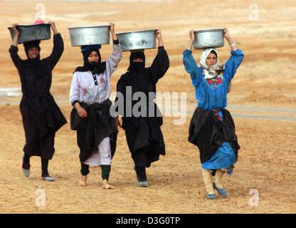 (Dpa) - eine Gruppe von irakischen Frauen gehen gemeinsam und Zinn Eimer auf dem Kopf während einer Aufklärungsmission von US-Marines an der 3. Licht Amoured Reconnaissance Battalion (3. LAR) rund 90 Kilometer südlich von Bagdad in der Nähe von Nu Maniyah, Irak, 2. April 2003. Die US-Marines bereiten auf die entscheidenden Vorstoß auf Bagdad nach Tagen der Ruhe. Stockfoto