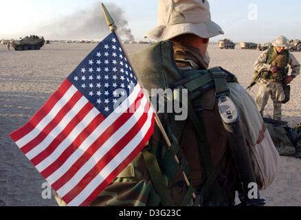 (Dpa) - ein US-Marine von der 3. Licht Amoured Reconnaissance Battalion (LAR), montiert mit seinem Rucksack und die US-Flagge, verlässt Camp Coyote in Richtung der Grenze zum Irak in Kuwait, 18. März 2003. Die Soldaten erwarten die Aufträge für den Einsatz von US-Präsident Bush nach Ablauf des Ultimatums 48 Stunden. Stockfoto