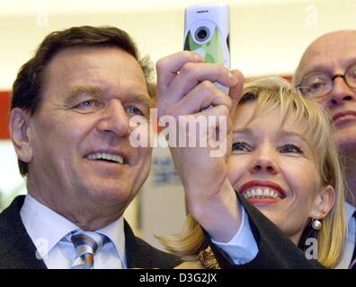 (Dpa) - Bundeskanzler Gerhard Schroeder und seine Frau Doris Schröder-Koepf Blick auf ein neues Mobiltelefon mit integrierter Kamera auf dem Marktstand von Nokia, bei der weltweit größten Computer Messe CeBIT in Hannover, 12. März 2003 zu handeln. Die CeBIT wird voraussichtlich vom 12. bis 19. März 2003 stattfinden. Mehr als 6.500 Unternehmen aus der ganzen Welt präsentieren ihre Produkte, die Stockfoto