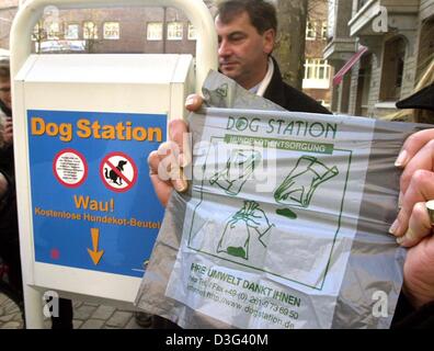 (Dpa) - hält eine Person eine Plastiktüte neben "Dog-Station" in Hamburg, Norddeutschland, 12. Februar 2003.  Die Plastiktüten haben sogar ein Diagramm gedruckt auf ihnen, ihren Gebrauch erklären.  Die Zeichen auf den Hund station liest "Dog Station, Wau!, Kostenlose Hundekot-Beutel" ("Dog Station, Wuff Wuff!, gratis Hund Kot Taschen).  In Zukunft sollen Hundebesitzer diese Taschen zu re verwenden Stockfoto