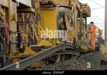 (Dpa) - steht einer der Arbeiter auf den Wiederaufbau Zug UM3 die neue Betonschwellen für die wichtigen Bahnstrecke zwischen Mainz und Köln, in der Nähe von Bornheim, Deutschland, 10. November 2003 liefert. Die Maschine wiegt 2.500 Tonnen und 750 m in der Länge misst. Es greift den alten Bahngleisen, legt sie beiseite und bringt die alten Schwellen. Dann die neue Gleise verlegt sind Out und wh Stockfoto