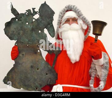 (Dpa) - der Bürgermeister, Roland Halang, verkleidet als Weihnachtsmann eine Jahrhunderte alte Wetterfahne in Form eines "Knecht Rupprecht hält" (Knecht Rupprecht) in Ilberstedt, Deutschland, 8. Dezember 2003. Untersuchungen zufolge stammt die Figur des Knecht Rupprecht aus Ilberstedt. vor 1000 Jahren in dieser Stadt, ein Priester des Namens Rupprecht oder Rupert gilt als eine Gruppe von 18 Pag verflucht haben Stockfoto