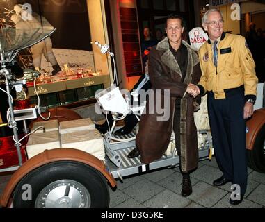 (Dpa) - sechs - Mal Formel 1 Welt Weltmeister Michael Schumacher (L) und Apollo 16 Astronaut Charles Duke (R) schütteln sich die Hände bei der Eröffnung des neuen OMEGA Store in München, 26. November 2003. Der Luxus-Uhrenhersteller Omega eröffnet eine neue Filiale in der noblen Maximilianstrasse (Maximilianstraße). Stockfoto