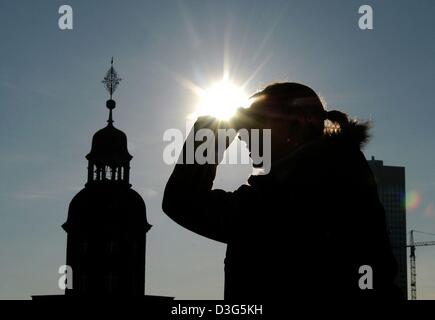 (Dpa) - eine Frau deckt ihre Augen mit der Hand gegen das helle Sonnenlicht in Frankfurt am Main, 26. November 2003. Im Hintergrund links den Turm der Chiesa di San Paolo (Paulskirche). Stockfoto