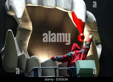 (Dpa) - Arbeiter Frank Mertens prüft eine dreidimensionale Wandmontage in Form einer Reihe von Zähnen eines Vampirs, in Hamburg, 31. Oktober 2003. Die vier Meter hoch und vier Meter Breite Mund wirbt den musical "Tanz der Vampire". In der Nacht, die sie mit Spezialeffekt Licht angestrahlt wird, gibt das es einen noch realistischeren Eindruck. Stockfoto