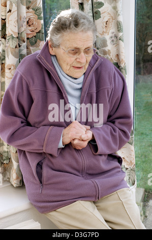 Ältere Frau trägt eine Fleece-Jacke & einen warmen Schal versucht, bei kaltem Wetter warm zu halten Stockfoto