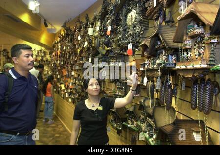 (Dpa) - der chinesische Hersteller Yeo berät Kunden aus Malaysia auf die Kuckucksuhr zu kaufen, in einem touristischen Geschäft in Titisee im Schwarzwald, Deutschland, 14. August 2003. Drei chinesische Verkäuferinnen sind spezialisiert auf Kunden und Touristen aus Asien. Die Kuckucksuhren sind ein Lieblings-Souvenir aus dem Schwarzwald. Stockfoto