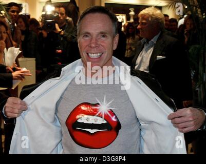 (Dpa) - US-Mode-Designer Tommy Hilfiger posiert mit einem T-shirt mit offenem Mund, am Eingang seines Ladens am Kuerfuerstendamm in Berlin, 14. Oktober 2003. Im Shop eröffnet er eine Ausstellung von Jeanswear entworfen von Berühmtheiten wie Ozzy Osbourne, Arnold Schwarzenegger und Whoopi Goldberg. Die Jeanswear werden später für einen guten Zweck versteigert. Stockfoto