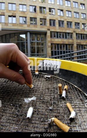 (Dpa) - ein Mann streckt eine Zigarette im Aschenbecher außerhalb eines Bürogebäudes in Frankfurt am Main, 16. November 2004. Arbeitgebern und Gewerkschaften in Deutschland sind derzeit diskutiert, ob Raucherpausen während der bezahlten Arbeitszeit erlaubt werden sollte. Arbeitgeber verlangen, dass Rauchen in den Büros komplett verboten werden. Stockfoto