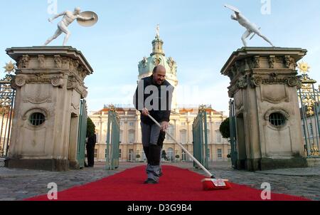 (Dpa) - ein Mitarbeiter fegt den roten Teppich vor Schloss Charlottenburg in Berlin, 20. Oktober 2004. Der deutsche Bundespräsident erhielt kurz danach einen Staatsbesuch am Schloss Charlottenburg, die derzeit als Residenz des Präsidenten dienen wird, während Schloss Bellevue Renovierungsarbeiten stattfinden. Stockfoto