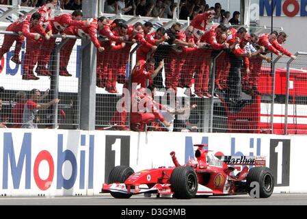 (Dpa) - ein weiteres Rennen, ein weiterer Sieg für Schumacher und sein Ferrari-Team. Deutsche Formel-1-Fahrer Michael Schumacher fährt nach dem Gewinn des Grand Prix von Deutschland in Hockenheim, Deutschland, 25. Juli 2004 jubelnden vorbei sein Ferrari-Team-Mechanikern. Die verteidigende Formel-1-Champion hat jetzt einen Rekord 11 der 12 Rennen dieser Saison gewonnen. Stockfoto