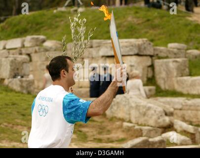 (Dpa) Griechische Speerwerfer Costas Gatsioudis trägt das Feuer während der Proben der Blitz-Zeremonie der Olympischen Flamme für Athen Olympischen Sommerspiele, vor dem Hera-Tempel im antiken Olympia auf Mittwoch, 24. März 2004. Stockfoto