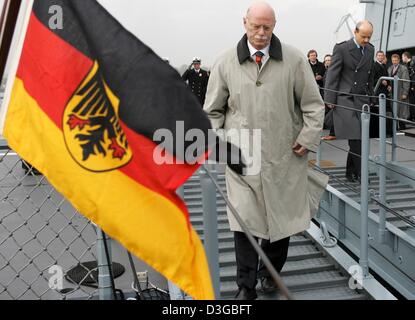 (Dpa) - Blätter Denfence Bundesminister Peter Struck nach hält eine Rede neben einer wehenden Bundesdienstflagge (Federal Service Flag) für die Einweihung der neuen Fregatte "Sachsen" (Sachsen) auf dem Marinestützpunkt in Wilhelmshaven, Deutschland, 4. November 2004. Die "Sachsen" ist ein Schiff der neuen F-124 Serie und gilt als eines der modernsten Fregatten in Europa. Es übernimmt Stockfoto