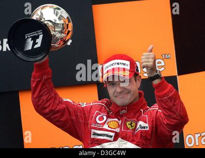 (Dpa) - brasilianischer Formel 1 pilot Rubens Barrichello (Ferrari) präsentiert stolz seine Trophäe nach dem dritten Platz in der brasilianischen Formel 1 Grand Prix auf der Rennstrecke Interlagos in der Nähe von Sao Paolo, Brasilien, 24. Oktober 2004. Stockfoto