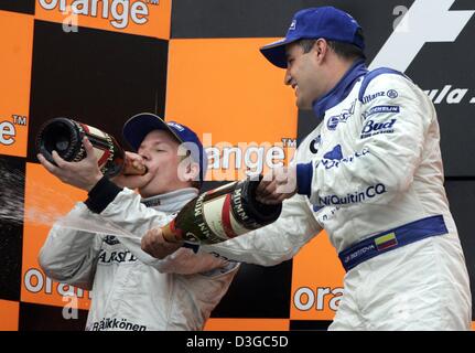 (Dpa) - kolumbianischer Formel1-Fahrer Montoya (R) von BMW-Williams auf dem Podium mit zweite platzierte beenden Kimi Raeikkoenen (L) von McLaren Mercedes feiert nach dem Gewinn der brasilianischen Formel Eins Grand Prix auf der Rennstrecke Interlagos in Sao Paulo, Brasilien, Sonntag, 24. Oktober 2004. Stockfoto