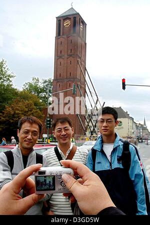 (Dpa) - drei chinesische Touristen haben sich fotografieren vor der strukturell beschädigte Kirchturm der katholischen St. Johann Baptist Kirche, genannt der "schiefe Turm von Köln" von vielen in der Südstadt Köln, Deutschland, 5. Oktober 2004. Es gibt Chancen, dass der Turm Teil einer Sightseeing-Tour in naher Zukunft werden. "Wenn der Turm in bleibt seiner Stockfoto