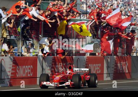 (Dpa) - team brasilianischen Formel 1 pilot Rubens Barrichello (Ferrari) Rennen vorbei an jubelnden Ferrari, als er großen Preis von China auf dem neuen Shanghai International Circuit in Shanghai, China, 26. September 2004 gewinnt. Stockfoto