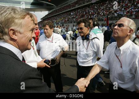 (Dpa) - Juergen Hubbert (R), Vorstandsvorsitzender der Mercedes-Benz Auto Group, schüttelt Hände mit FIA Chef Max Mosley (L) während der chinesischen Formel 1 Grand Prix auf dem neuen Shanghai International Circuit in Shanghai, China, 26. September 2004. Im Hintergrund stehen Mercedes Motorsport Direktor Norbert Haug (L) und BMW technische Direktor Mario Theissen (R). Stockfoto