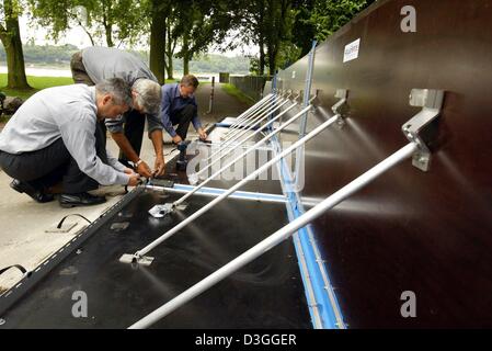 (Dpa) - drei Mitglieder des Referats Flood Schutz Köln eine neue Hochwasserschutzmauer aus norwegischen Firma AquaFence AS an den Ufern des Rheins in Köln, Deutschland, 24. August 2004 montieren. Es dauert 10 Personen ca. 1 Stunde zum Einrichten einer 100 Meter langen Wand. Die Wand hat eine lange Lebensdauer und kann wiederverwendet werden. Seine tatsächliche Wirksamkeit wird jedoch nicht bis zum nächsten Flo bekannt sein Stockfoto