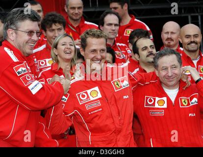 (Dpa) - deutsche Ferrari Formel1-Fahrer Michael Schumacher (C) zusammen mit Ferrari Team in Richtung Jean Todt (R) und Chef-Techniker Ross Brawn nach der belgischen Formel Eins Grand Prix in Spa, 29. August 2004 feiert. Michael Schumacher wurde Zweiter im Grand Prix, Clinchen eine noch nie dagewesene siebten WM Titel trotz nicht gerade zum zweiten Mal gewinnen Stockfoto