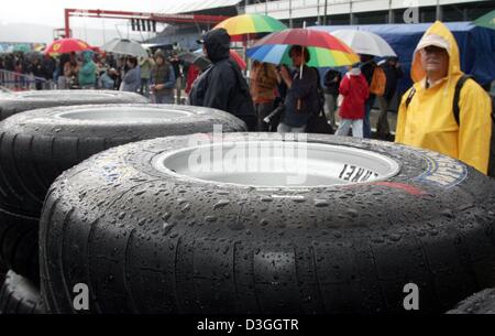 (Dpa) - im strömenden Regen laufen Formel-1-Fans durch die Boxengasse auf die Rennstrecke in Spa-Francorchamps, Belgien, 26. August 2004. Am Sonntag 29. August statt findet auf dem Golfplatz die Formel 1 Rennstrecke in Belgien. Stockfoto