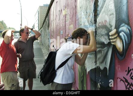 (Dpa) - ein amerikanischer Tourist nimmt ein Bild durch eine Öffnung der Berliner Mauer, 12. August 2004. Die so genannte "East-Side-Gallery" steht unter Denkmalschutz und bildet den am längsten noch bestehenden Teil der ehemaligen Trennlinie, dass getrennte Ost- und West-Berlin. Stockfoto