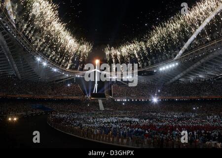 (Dpa) - Feuerwerk den Himmel über dem Olympiastadion zu beleuchten, wie das Olympische Feuer während der Eröffnungsfeier der Olympischen Spiele 2004 in Athen, Freitag, 13. August 2004 beleuchtet ist. Stockfoto