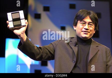(Dpa) - Satoru Iwata, Präsident von Nintendo, Lächeln als Geschenk das neue Handyspiel paddeln Nintendo DS (Dual Screen) während der "Electronic Entertainment Expo" (E3), Fachmesse für Computer- und Videospiele, in Los Angeles, Kalifornien, USA, 11. Mai 2004. Stockfoto