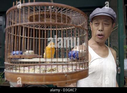 (Dpa) - ein Mann schaut seinen Kanarienvogel sitzt in einem Käfig im alten Dong Cheng District in Peking, China, 16. Juli 2004. Quartier 100-Year-Old Dong Cheng besteht aus winzigen Wohnungen, liegt am kleinen und engen Gassen, die dazu bestimmt sind, werden abgerissen, um Platz für moderne Wohnhochhäuser machen. Die Anwohner erhalten staatliche Subventionen um ab Stockfoto