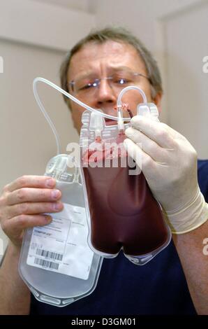 (Dpa) - Dirk Schrader, Leiter der tierärztlichen Klinik für Kleintiere, hält einen Kunststoffbehälter gefüllt mit gespendetes Blut von einem Hund in Hamburg, Deutschland, 18. Mai 2004. Tierarzt Schrader hat eine Blutbank für Hunde in seiner Praxis etabliert. Für viele Hunde ist die Behandlung mit Blutplasma, Blut ohne Blutzellen, ihre letzte Chance zu überleben. Stockfoto