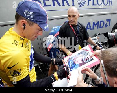 (Dpa) - US Postal team Fahrer und Tour de France Sieger Lance Armstrong (L) von den US-Zeichen ein Autogramm von seinem Leibwächter vor der fünften Etappe der Tour de France-Radrundfahrt in Amiens, Frankreich, 8. Juli 2004 beobachtet. Die 200,5 km lange fünfte Etappe der Tour de France führt die Radfahrer von Amiens nach Chartres. Stockfoto