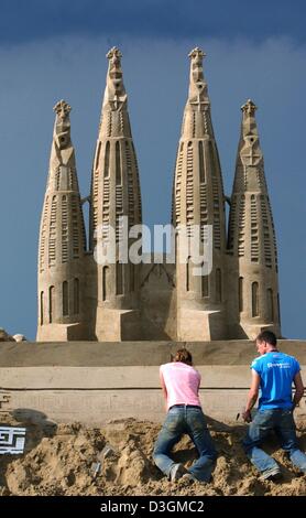 (Dpa) - Sand Bildhauer den letzten Schliff auf den Türmen der Kathedrale Sagrada Familia am Strand in Travemünde, Deutschland, 5. Juli 2004. 75 so genannte Carver aus 13 Ländern arbeiten an ihre Skulpturen für den 3. deutschen Sandskulpturenfestival, Sand World, die unter dem Motto "Mythos von Olympia" in diesem Jahr sein wird. Das Festival mit der Wahrzeichen der Veranstaltungsorte Stockfoto