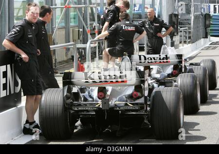 (Dpa) - McLaren-Mercedes Mechaniker steht neben den Rennwagen der Formel-1-Rennfahrer Kimi Raeikkoenen und David Coulthard auf der Rennstrecke Magny Cours in Frankreich, 1. Juli 2004. Der französische Grand Prix werden im Gange Sonntag, 4. Juli 2004. Das Team nutzt ein völlig neues Modell zum ersten Mal beim Rennen. Stockfoto