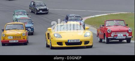 (Dpa) - A Porsche Carrera GT (C) mit 612 PS führt das Feld der Trabis während der 5. Trabirallye auf dem Testgelände der Porsche Werk in Leipzig, Deutschland, 17. Juni 2004. Rund 54 Trabis, ehemalige deutsche Automarke, beteiligte sich an einer Rallye feiert 100 Jahre Auto Designlösungen im Freistaat Sachsen und Rennen gegen Porsche Carrera GT. Stockfoto