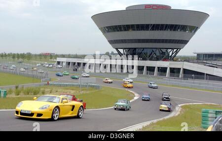 (Dpa) - A Porsche Carrera GT (L) mit 612 PS führt das Feld der Trabis während der 5. Trabirallye auf dem Testgelände der Porsche Werk in Leipzig, Deutschland, 17. Juni 2004. Rund 54 Trabis, ehemalige deutsche Automarke, beteiligte sich an einer Rallye feiert 100 Jahre Auto Designlösungen im Freistaat Sachsen und Rennen gegen Porsche Carrera GT. Stockfoto