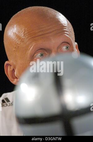 (Dpa) - italienische UEFA Schiedsrichter Pierluigi Collina (überdacht) sitzt im Rahmen einer Pressekonferenz hinter "Roteiro", den offiziellen Ball der Euro 2004 Fußball Meisterschaft in Espinho, Portugal, 9. Juni 2004. Collina ist einer der insgesamt zwölf Schiedsrichter während der Meisterschaft, die gerade ihre letzte allgemeine Ausbildung abgeschlossen haben. Collina wird das Eröffnungsspiel zwischen Schiedsrichter Stockfoto