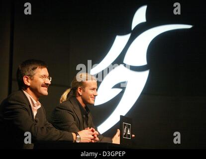 (Dpa) Englische Fußball-star David Beckham (rechts) und Adidas Vorstandsvorsitzenden Herbert Hainer sitzen vor neuen Logo im Rahmen einer Pressekonferenz am Sitz Adidas in Herzogenaurach auf Mittwoch, 3. März 2004. Das Design des Logos wurde inspiriert von Beckhams Marke Freistöße und erscheint auf entworfenen Kollektionen, die später in diesem Jahr offenbar werden werden. Stockfoto