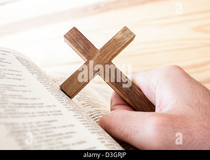 Mann, hält das Kreuz in der Hand, mit der Bibel unter Stockfoto