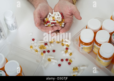 Senior Hände Holding Pillen mit Pillen auf einen Tisch und Verschreibung Flaschen mit einem weißen Hintergrund Stockfoto