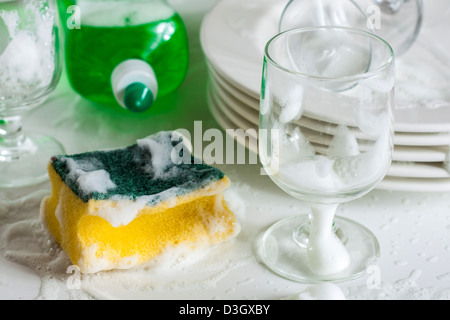 Gläser und Teller mit Wasser und Spülmittel waschen Stockfoto