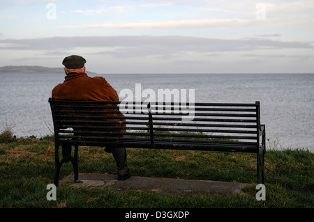 allein auf eigenen Sit Bank Blick auf Meer Ozean sitzen alte älterer Mann einsamer Single denken betrachten in Erinnerungen schwelgen Abends Sonnenuntergang Winter Stockfoto