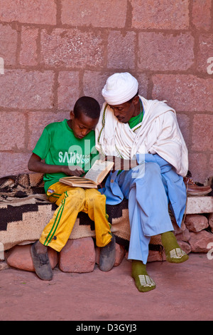 Junge-Lesung mit Priester, Wette Mercurios Kirche, Lalibela, Äthiopien Stockfoto