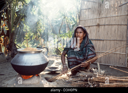 Dorf Frau ankochen Reis vor dem Trocknen in der Sonne.  Parboiled-Reis kocht schneller, ist fester und weniger klebrig. Bangladesch Stockfoto