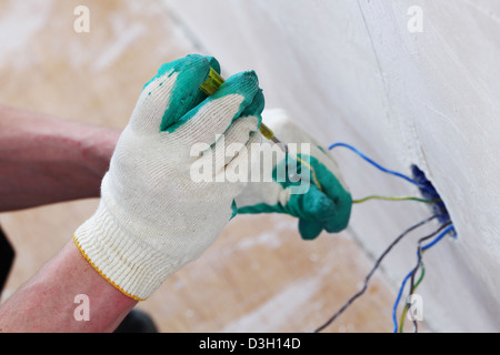 Arbeiter setzt die Leitungen in der Wand Stockfoto